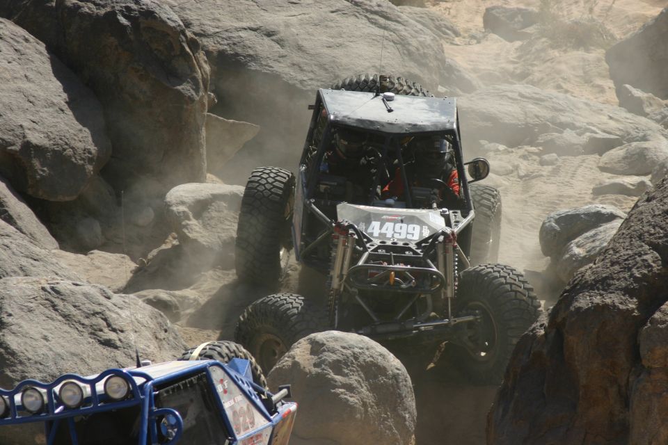 Off-road buggy with number 4499 on front climbing over rocks, another buggy visible in foreground