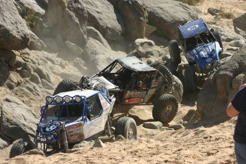1992 Jeep Wrangler - Multiple off-road vehicles tackle a challenging rocky course during a competition.