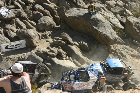 1992 Jeep Wrangler - Multiple off-road vehicles tackle a challenging rocky terrain during a race event.
