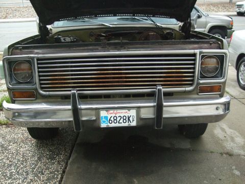 1979 Ford Bronco - Front view of a 1973 Chevrolet C/K pickup truck, hood up, showing rusty grille and chrome bumper.
