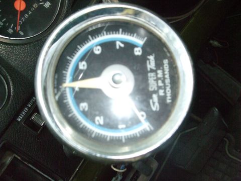 1979 Ford Bronco - Close-up of a vehicle's dashboard showing a tachometer and a switch.