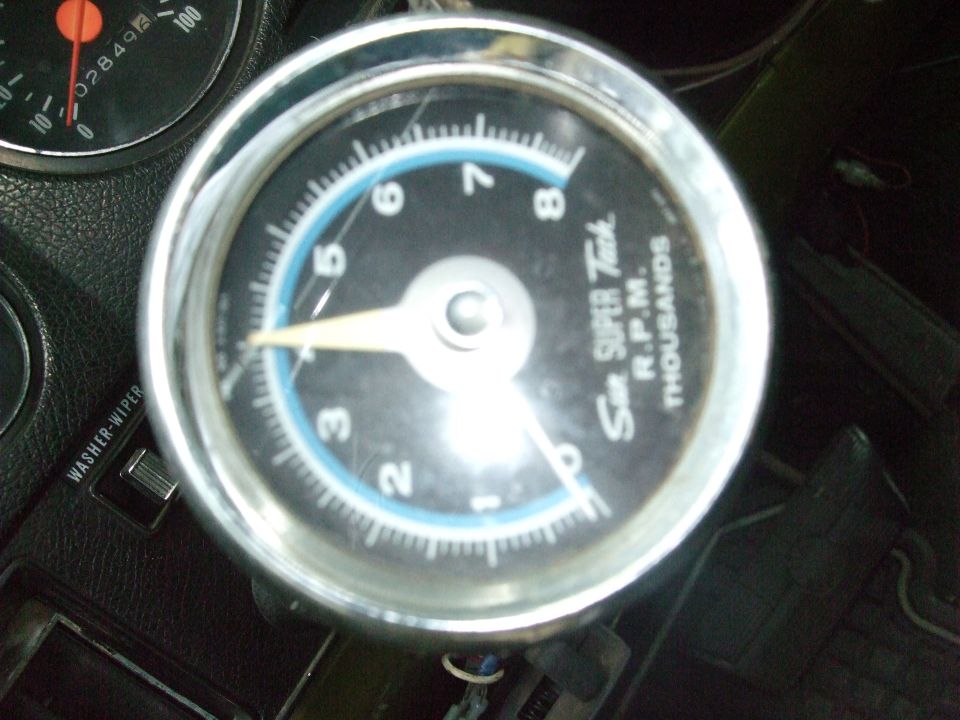 Tachometer gauge with blue ring and white needle, next to a washer-wiper switch