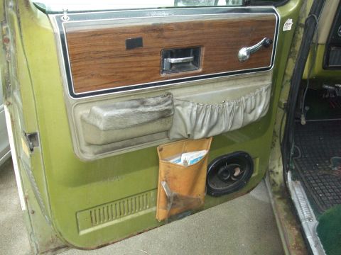 1979 Ford Bronco - Interior door panel of a green truck, wood grain trim and a map pocket.