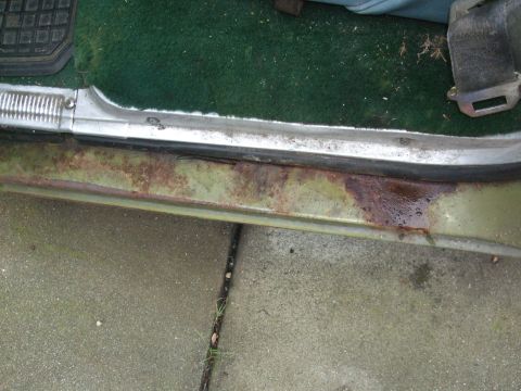 1979 Ford Bronco - The door sill of a vehicle shows significant rust and water damage, with green carpet visible inside.