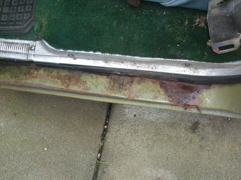 close-up of rusted door sill and green carpet inside a vehicle