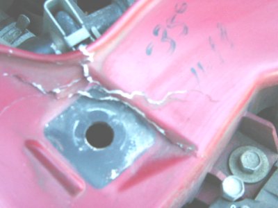 1997 Ford Taurus - Close-up of a damaged red metal part in an engine bay.