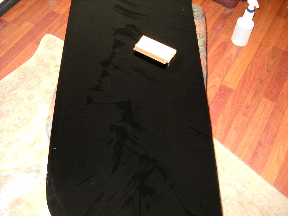 Black window tint film on a flat surface with a squeegee and spray bottle nearby