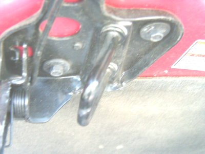 1997 Ford Taurus - Close-up view of a red vehicle's hood latch mechanism, showing metal parts and fasteners.