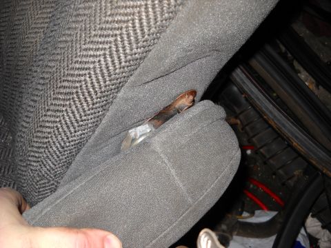 1993 Ford C-150 (Centurion Conversions) - A hand is shown near the upholstery of a car seat, revealing a worn metal component.