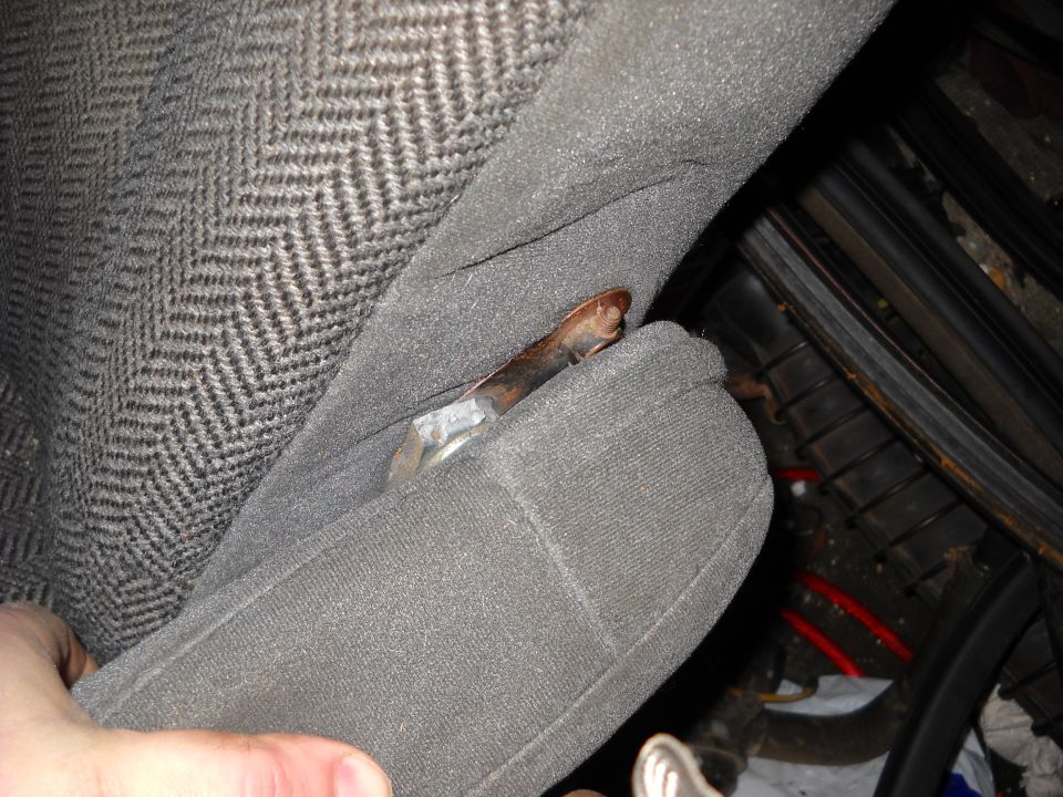 Close-up of gray patterned car seat fabric with a rusty metal lever visible