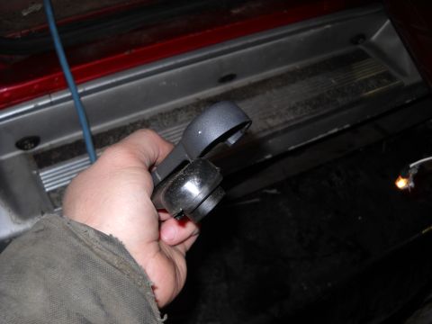 1993 Ford C-150 (Centurion Conversions) - A person holds a broken interior door handle part, with the vehicle's door sill visible in the background.