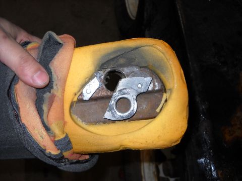 1993 Ford C-150 (Centurion Conversions) - The internal mechanism of a car armrest is revealed, with damaged foam and exposed metal parts.