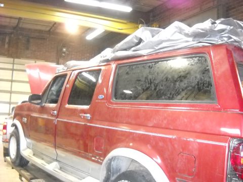 1993 Ford C-150 (Centurion Conversions) - This red extended cab truck with a cap is covered by a tarp, obscuring some of its details.