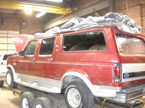 1993 Ford C-150 (Centurion Conversions) - Red SUV on a trailer, side view, with its hood open and a tarp covering the roof.