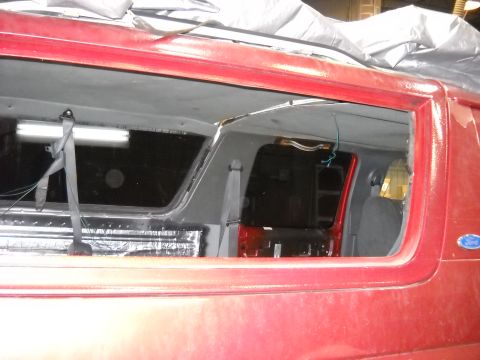 1993 Ford C-150 (Centurion Conversions) - Interior view of a red van with a removed window, revealing insulation and seating.