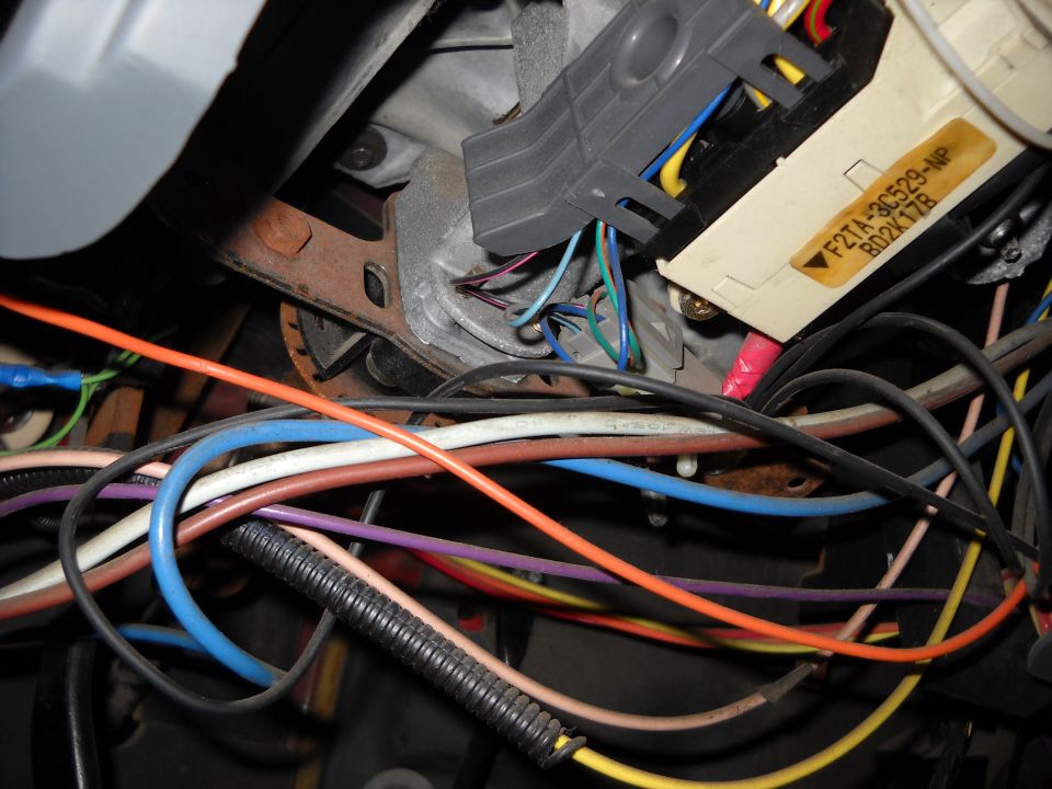 Close-up of a tangled vehicle steering column wiring harness with a yellow label reading F2TA-3C529-NP B02K17B