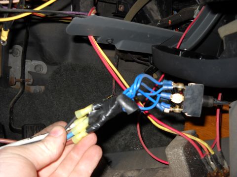 1993 Ford C-150 (Centurion Conversions) - Close-up of aftermarket wiring modifications near the steering column, showing a hand connecting wires to a switch.