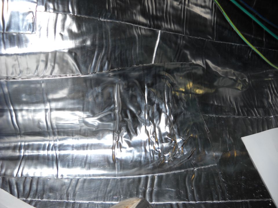 Shiny silver insulation material covers a wall, with some wires visible at the top right