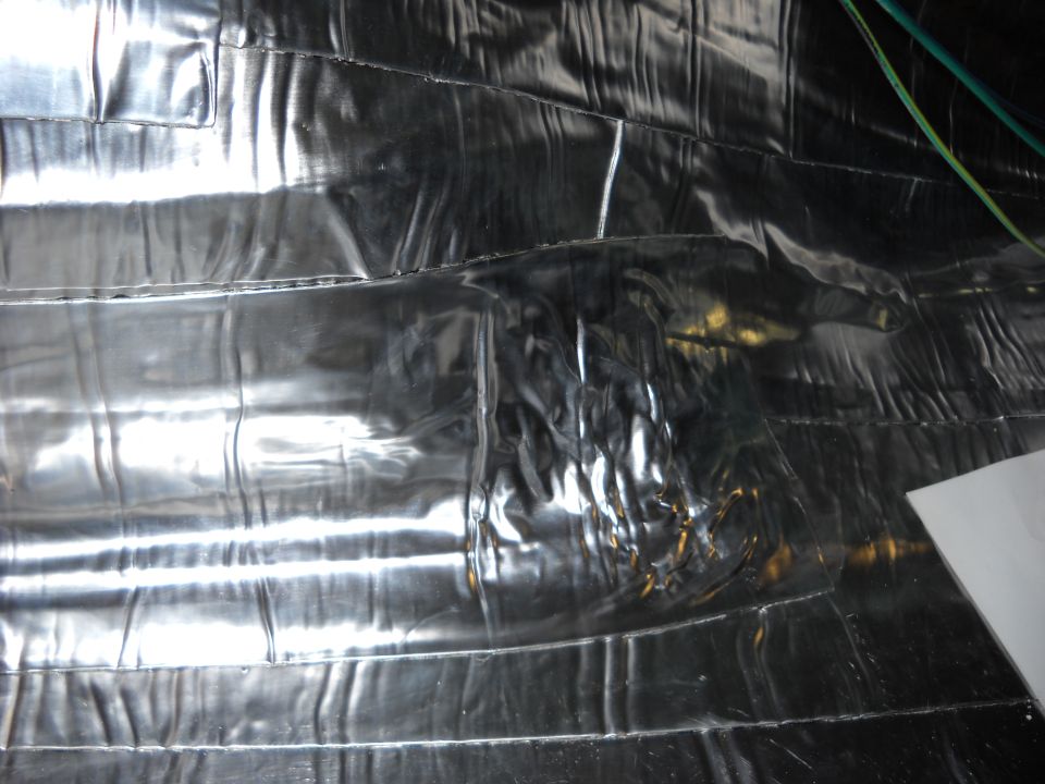 Shiny, crinkled insulation material covers the interior walls and ceiling