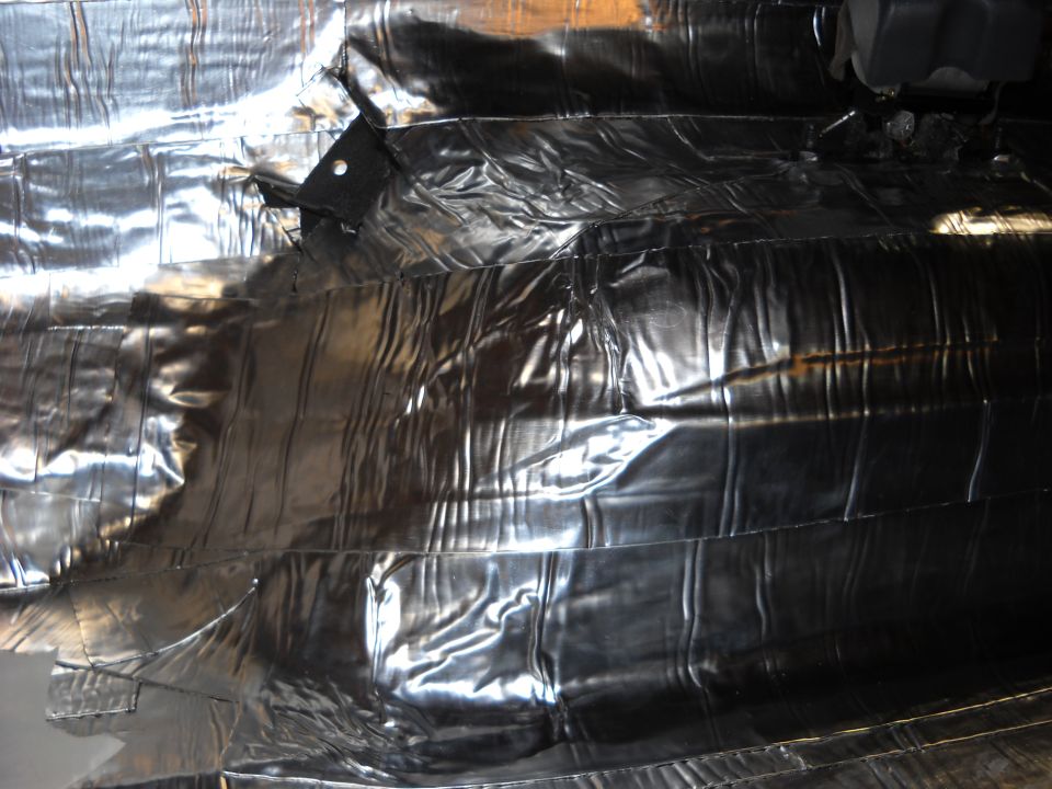 Shiny, crinkled insulation material covering the underside of a vehicle
