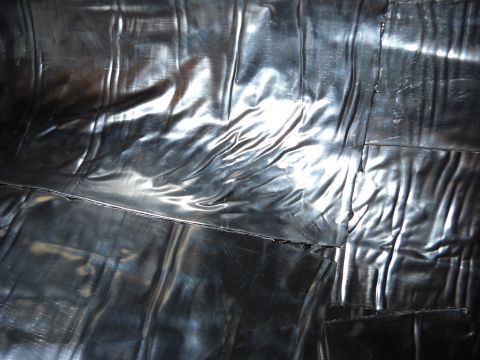 1993 Ford C-150 (Centurion Conversions) - The image shows a close-up view of wrinkled black plastic material, possibly a tarp or cover.