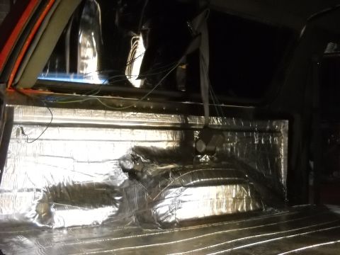 1993 Ford C-150 (Centurion Conversions) - The interior of a vehicle is covered in silver insulation, with wiring and a speaker visible.