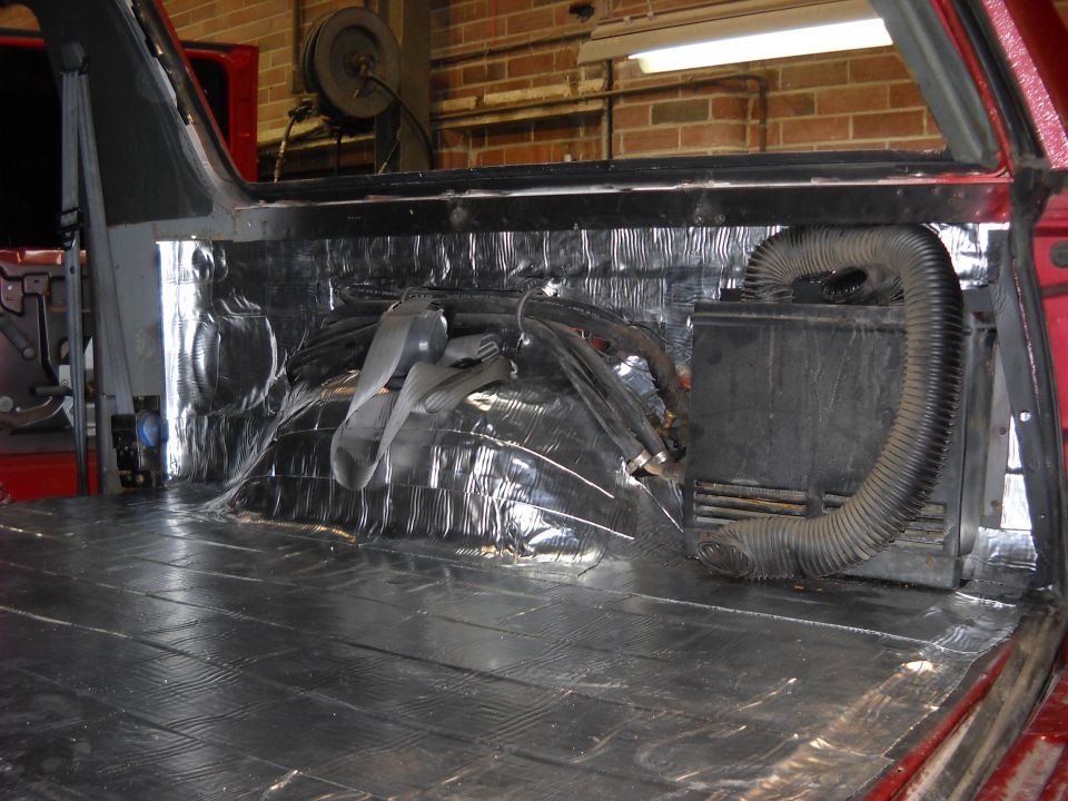 Vehicle interior with sound deadening on floor and walls, showing ducting and wiring