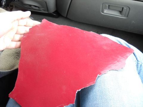 1993 Ford C-150 (Centurion Conversions) - A fragment of red painted metal is held by a hand inside a vehicle.