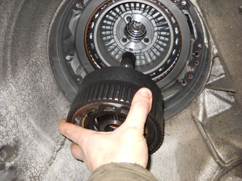 1993 Ford C-150 (Centurion Conversions) - Close-up of a hand holding a transmission part, with internal components visible.