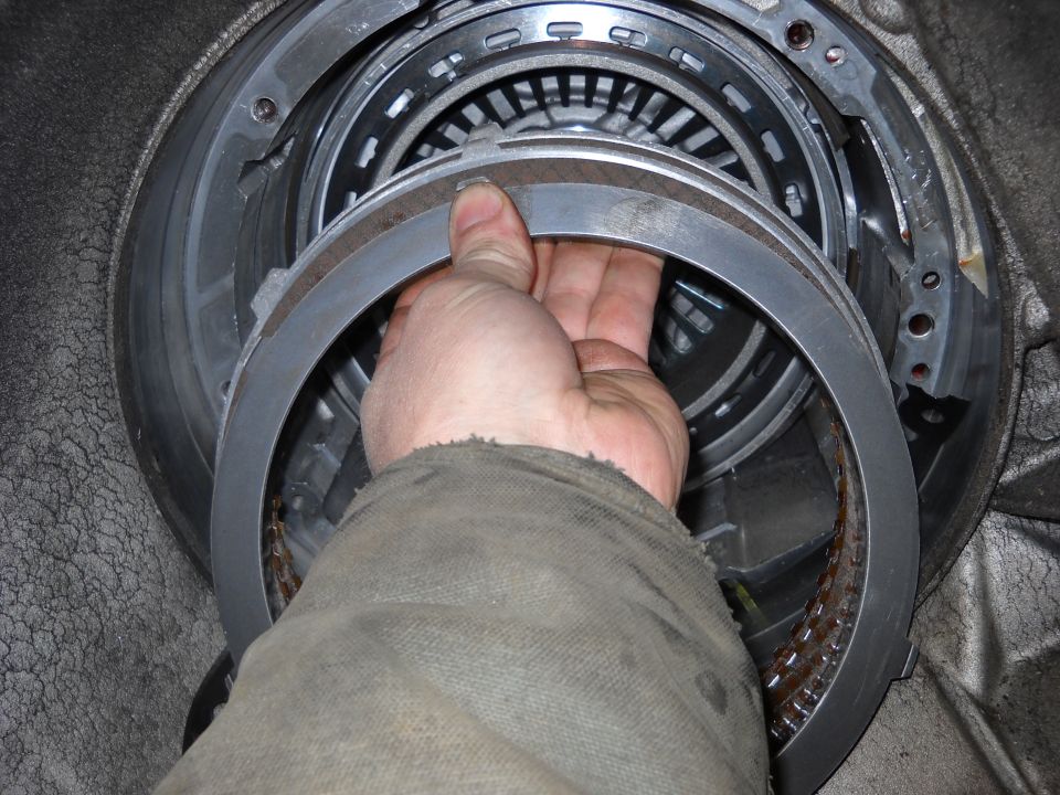Hand holding a metal ring inside a transmission assembly
