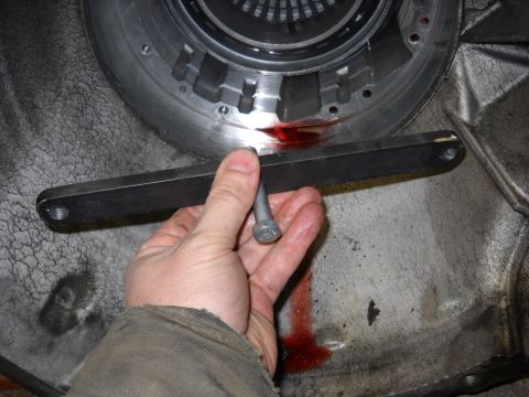 1993 Ford C-150 (Centurion Conversions) - A hand holds a bolt near a transmission housing, with red fluid leaking out.