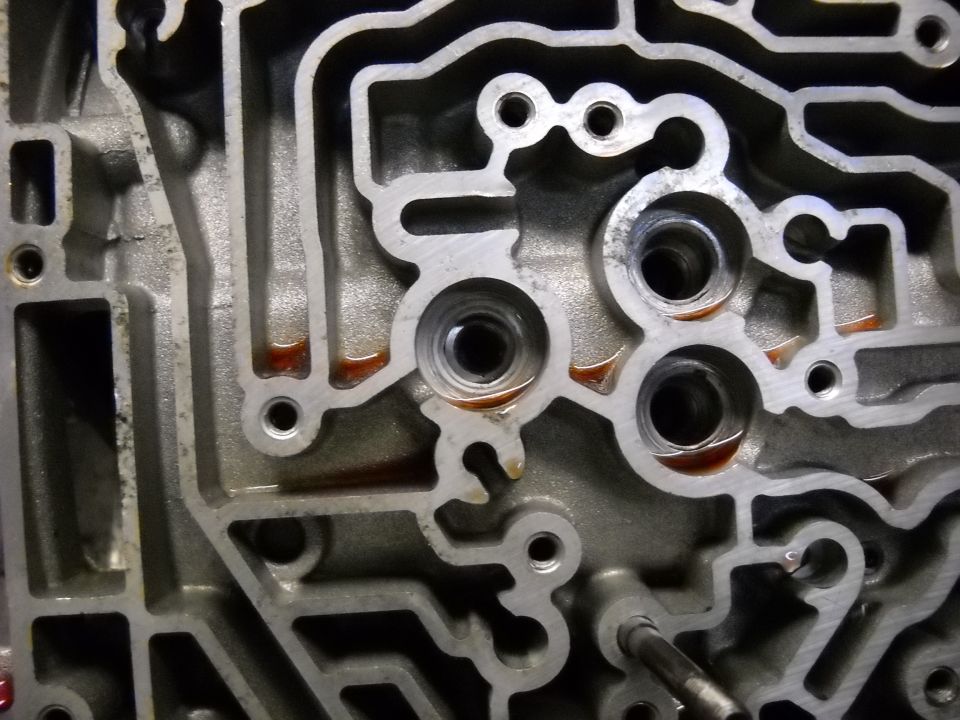 Close-up of an automatic transmission valve body with reddish fluid in channels