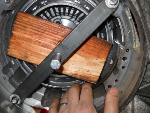 1993 Ford C-150 (Centurion Conversions) - Close-up of a transmission part being worked on with tools and wooden blocks.