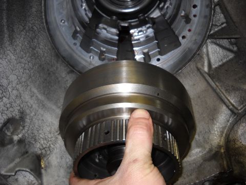 1993 Ford C-150 (Centurion Conversions) - Close-up of a hand holding a transmission torque converter during a rebuild.