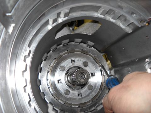 1993 Ford C-150 (Centurion Conversions) - A hand uses a screwdriver to manipulate internal components within a vehicle's automatic transmission.