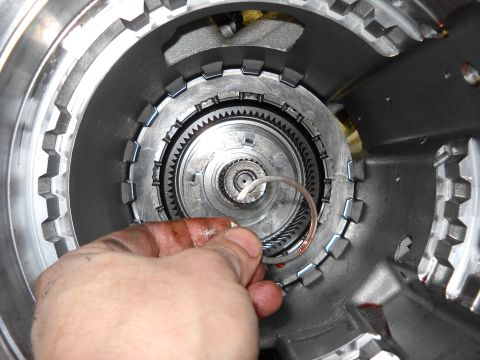 1993 Ford C-150 (Centurion Conversions) - Close-up of a transmission part, possibly a clutch or seal, being handled during a rebuild.