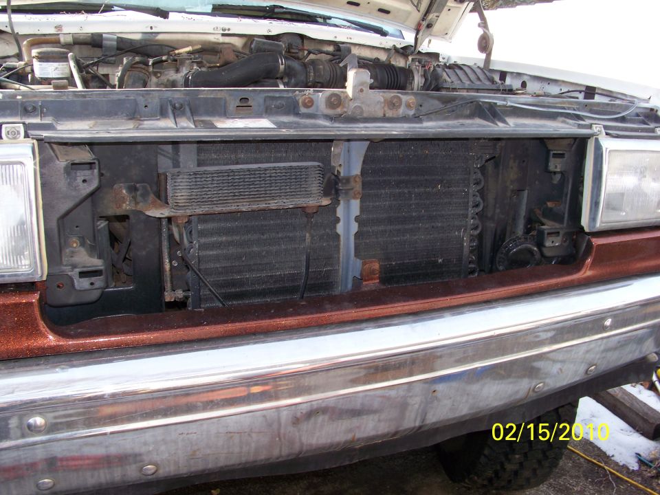 Truck front end, hood up, showing radiator and engine components. Chrome bumper visible
