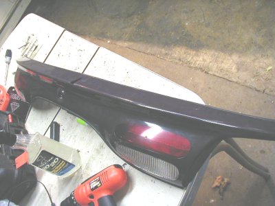 1997 Ford Taurus - Car taillight assembly on a workbench, with a drill and cleaning spray nearby.
