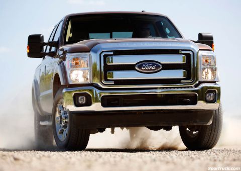 2008 Ford F-250 - Front view of a brown Ford Super Duty truck driving on a dirt road, kicking up dust.