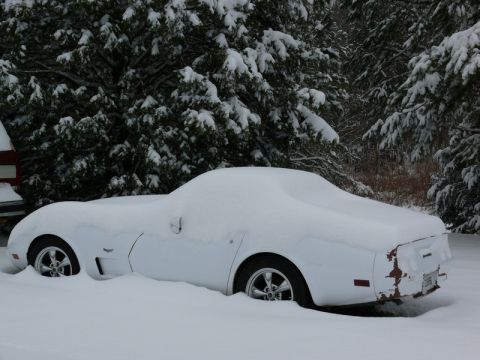 1976 Chevrolet Corvette - A white 1976 Chevrolet Corvette sits buried in snow, with only its wheels and the outline of its body visible.