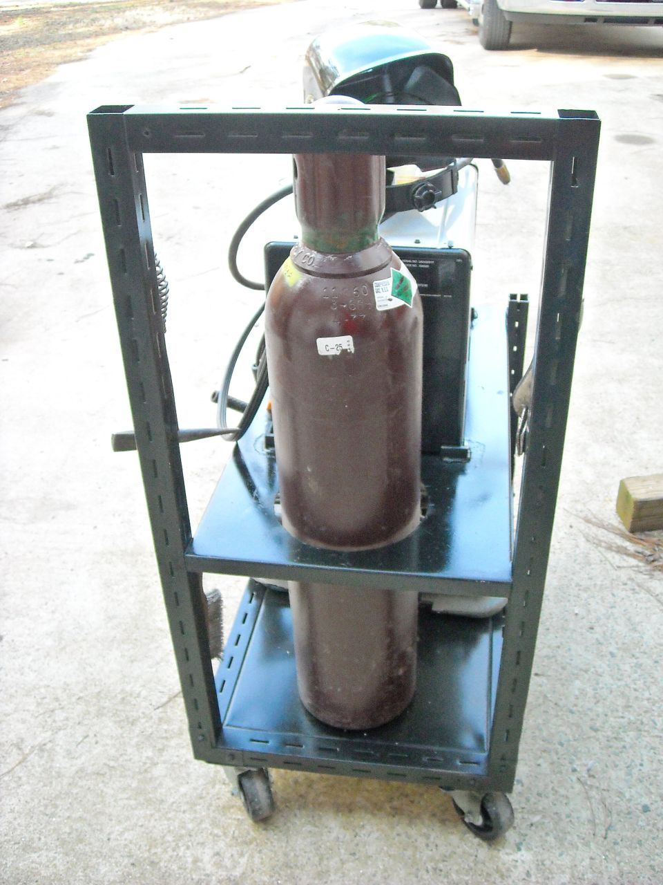 Welding cart with two gas cylinders and a welding helmet