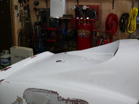 1976 Chevrolet Corvette - The front of a car is shown in a workshop setting, with tools and equipment in the background.