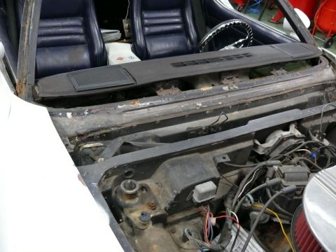 1976 Chevrolet Corvette - View of the interior and engine bay of a 1976 Chevrolet Corvette, showing seats and exposed engine components.