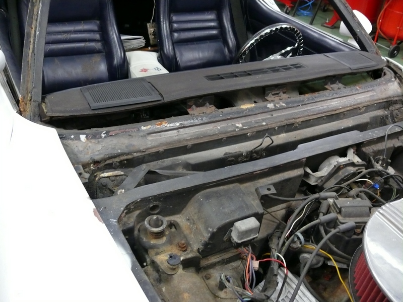 1976 Chevrolet Corvette interior showing blue seats, dashboard, and engine bay with wiring