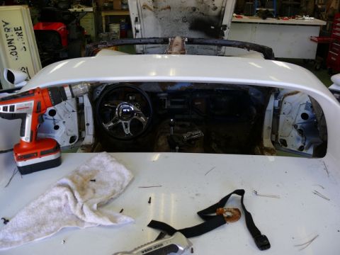 1976 Chevrolet Corvette - The interior of a car is being worked on, with tools and parts scattered around the dashboard area.
