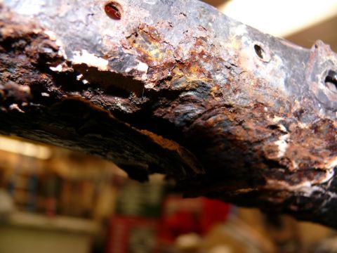 1976 Chevrolet Corvette - Close-up of heavily corroded metal, likely a vehicle frame part, showing significant rust damage.