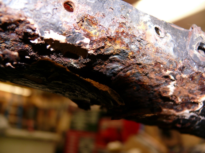Heavily rusted metal frame with visible holes and peeling paint