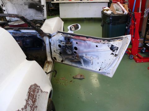 1976 Chevrolet Corvette - Interior of a car door, showing exposed mechanics and wiring. Exterior fender shows rust damage.