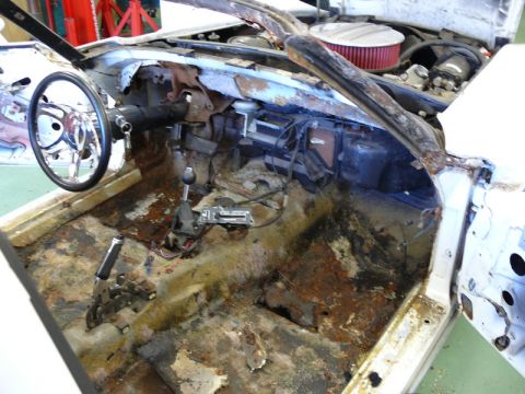1976 Chevrolet Corvette - The interior of a car shows significant rust and damage, indicating it is in need of restoration.