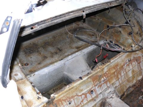 1976 Chevrolet Corvette - The rear cargo area of a 1976 Chevrolet Corvette shows significant rust and exposed wiring.